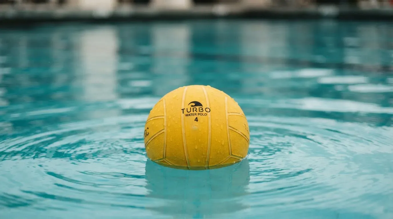 Ein gelber Ball treibt auf ruhigem türkisfarbenem Beckenwasser, feine Wellen im weichen Licht.