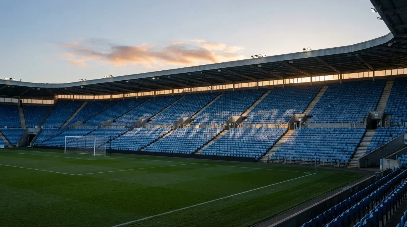 Eine leere Stadiontribüne bei Sonnenaufgang aus der Ferne, lange Schatten fallen über die Sitzreihen