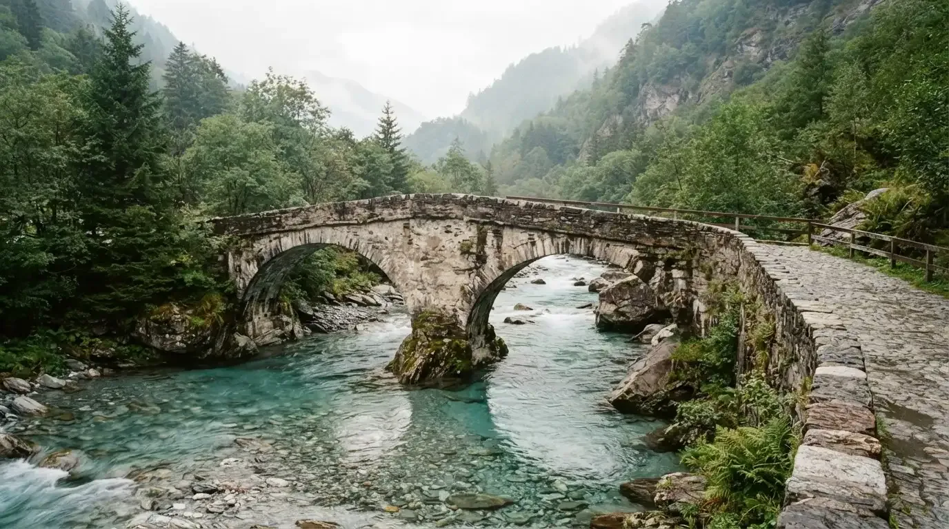 Eine alte Steinbrücke überspannt einen Gebirgsfluss, im Hintergrund steigen bewaldete Hänge an.