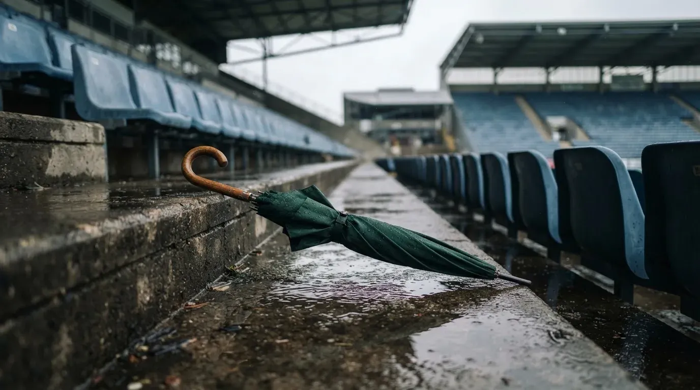 Ein Regenschirm liegt auf einer nassen Treppe zwischen leeren Zuschauerrängen.